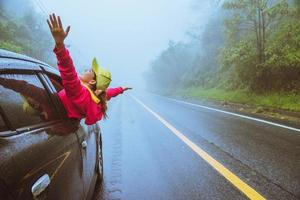 le donne asiatiche viaggiano rilassarsi durante le vacanze. guidare un'auto viaggiando felice. in mezzo alla nebbia piovosa. foto