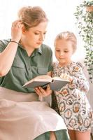 madre mamma figlia bambino a casa leggere il libro foto