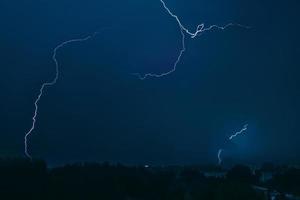 fulmine nel cielo sopra la città. lampi luminosi nella notte oscura. nubi temporalesche e scariche elettriche nell'atmosfera. foto