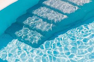 gradini della piscina sott'acqua. scale in piscina con acqua turchese in una giornata di sole.