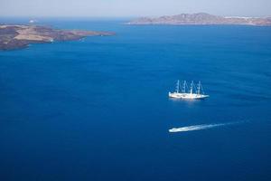 bellissima baia con barche a vela, isola di santorini grecia mare blu profondo baia con scogliere e foschia mattutina foto