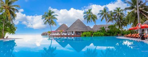 paesaggio del turismo all'aperto. lussuoso resort sulla spiaggia con piscina e sedie a sdraio o lettini ombrelloni con palme e cielo blu, orizzonte marino. l'isola estiva rilassa i viaggi e le vacanze idilliache