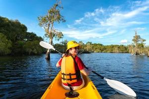 donna felice in kayak con barca in kayak nel lago nuture dietro il mare e la spiaggia prima del tramonto per rilassarsi e sport acquatici estremi foto