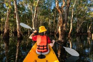 donna felice in kayak con barca in kayak nel lago nuture dietro il mare e la spiaggia prima del tramonto per rilassarsi e sport acquatici estremi foto