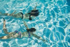 due ragazze che nuotano sott'acqua in una piscina privata in una giornata di sole foto