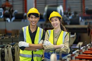 ritratto di un giovane team di lavoratori tecnici ingegneri asiatici sorridenti all'interno della linea di produzione della fabbrica di produzione