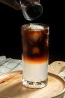 miscelazione fresca di caffè arabica con succo di cocco dolce per l'assistenza sanitaria da bere a casa. bevande in estate su sfondo scuro copia spazio. foto