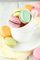 macarons colorati francesi in tazza su fondo di legno bianco foto