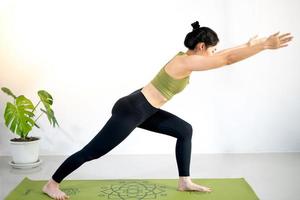 donna che fa yoga sul tappetino da yoga verde per meditare ed esercitarsi in casa. foto