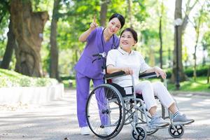 infermiera asiatica che si prende cura di una paziente di mezza età nel parco foto