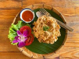 riso frittata di maiale tritato con cucchiai e forchette per salsa di peperoncino e verdure decorative che erano nei piatti sul tavolo di legno. foto