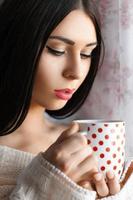 bella ragazza che beve caffè vicino alla finestra foto