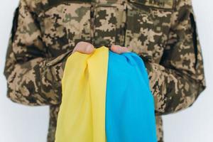 Soldato patriota ucraino in uniforme militare che tiene una bandiera gialla e blu su sfondo bianco foto