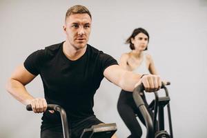 giovane uomo e donna che usano la bici ad aria per l'allenamento cardio presso la palestra di cross training foto