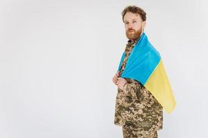 Soldato patriota ucraino in uniforme militare che tiene una bandiera gialla e blu su sfondo bianco foto