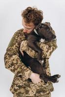 il soldato ucraino in uniforme militare tiene un cane in braccio su uno sfondo bianco foto