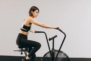 donna crossfit che fa un intenso allenamento cardio su cyclette foto