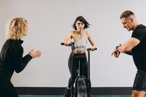 donna che si esercita sulla bici dell'aria in palestra con gli amici che motivano. foto