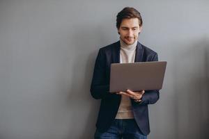 immagine di giovane uomo d'affari allegro in giacca e cravatta che tiene e utilizza il laptop nell'ufficio moderno foto