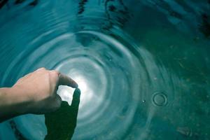 le mani immerse nell'acqua azzurra fino alle onde. foto