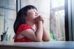 bambina che prega a casa, pura fede del bambino, concentrazione sul viso. foto