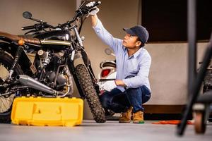 concetti di riparazione e manutenzione, uomo che ripara la motocicletta in officina, riparazione meccanica e controllo della moto del sistema frenante nel garage dell'officina foto