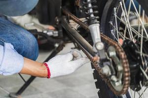 meccanico che ripara la moto nel garage dell'officina, uomo che ripara la motocicletta in officina, concetti di riparazione e manutenzione foto