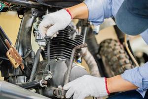 uomo che ripara moto in officina, meccanico che ripara moto nel garage dell'officina, concetti di riparazione e manutenzione foto