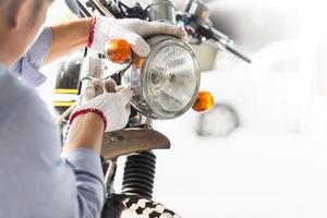 meccanico che ripara moto in officina, uomo che ripara moto in officina, riparazione e manutenzione foto