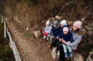 madre con quattro bambini seduti su una panchina al parco znojmo nella repubblica ceca foto