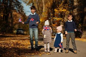 festa nazionale del regno unito. quattro bambini con bandiere britanniche nel parco autunnale. Britishness che celebra il Regno Unito. foto