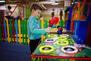 il ragazzo gioca a colpire la macchina da gioco del criceto nel parco giochi al coperto. foto