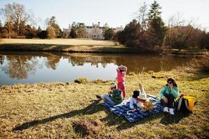 madre con quattro bambini che fanno picnic vicino a pound al parco di lednice contro il castello, repubblica ceca. foto