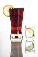 bicchiere di cola con fette di limone e colpo di vodka
