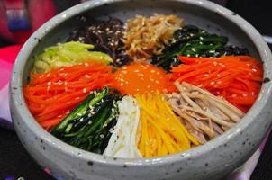 Bibimbap in una ciotola di pietra riscaldata, piatto coreano, da vicino
