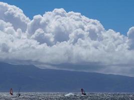 nuvole drammatiche tre windsurfisti acqua blu foto