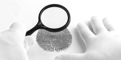 esperto di criminologia attraverso una lente d'ingrandimento guardando un'impronta digitale. foto