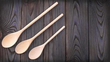 tre cucchiai di legno su un tavolo di legno scuro con spazio per la copia foto