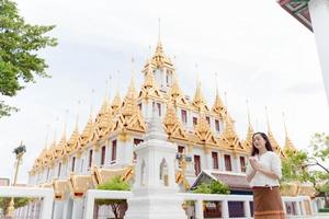 Asia donna che indossa abiti tradizionali della Thailandia pregando a Wat Ratchanatdaram una famosa attrazione turistica e luoghi di interesse a Bangkok in Thailandia foto