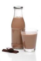 bottiglia e bicchiere di latte al cioccolato su sfondo bianco foto
