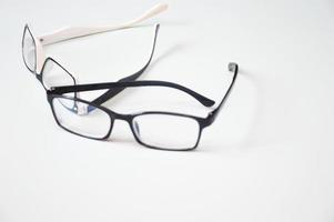 occhiali per la correzione della vista con freccette aperte, adagiati su uno sfondo bianco. ottica, cornici, accessori, oftalmologia. foto