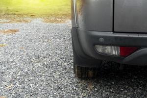in basso del parcheggio grigio sul lato posteriore dell'auto su un ampio pavimento di ghiaia. bianco sfocato di erba verde. l'ambiente dopo la pioggia tutta l'area è bagnata dalla pioggia. foto