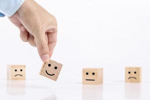 l'uomo d'affari sceglie un sorriso icone emoticon faccia felice simbolo sul blocco di legno, servizi e concetto di indagine sulla soddisfazione del cliente foto