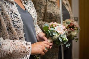 primo piano delle mani a treccia con un delicato bouquet da sposa foto