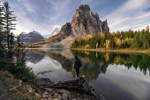 viaggiatore in piedi sul legname nel lago dello sprazzo di sole sul parco provinciale di assiniboine foto