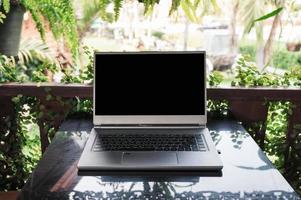 laptop grigio moderno aperto sul tavolo di vetro nel giardino di primavera foto