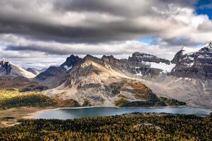 montagne rocciose con luce solare e lago cupo nel parco provinciale di assiniboine foto