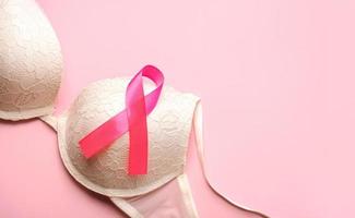 concetto di cancro al seno. reggiseno da donna e nastro rosa simbolo consapevolezza del cancro al seno con spazio per il testo foto