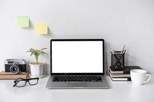 spazio di lavoro moderno ed elegante mock up con laptop e forniture per ufficio da scrivania con sfondo bianco e spazio per la copia foto