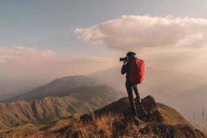 giovane viaggiatore con zaino che scatta una foto sulla montagna, concetto di stile di vita di viaggio avventuroso